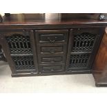 A Continental style stained pine cabinet with drawers and wrought iron doors.135x45cm.
