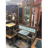 An Edwardian oak hall stand with a ceramic tile inset marble top and turned supports.