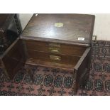 An oak collectors cabinet with brass inset handles and three graduating drawers on cabriole legs