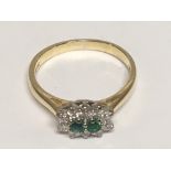 A yellow gold ring set with two Emerald and diamonds. Ring size P.