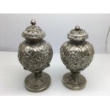 A pair of ornate white metal (tested silver) pepperetts with lead weighted bases.