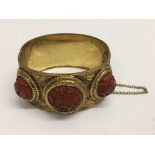 A Victorian gilt metal bangle set with cinnabar type roundels - NO RESERVE