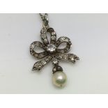 A small Edwardian diamond and blue seed pearl set bow pendant.