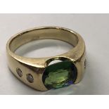 An 18carat Gold gents ring set with a green tourmaline flanked by diamonds ring size P.