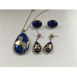 A oval lapis lazuli pendant with gold overlay design of a unicorn on a 14 ct gold chain with a
