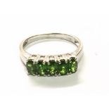 A 9carat white gold ring set with a row of green Peridot. Ring size N.