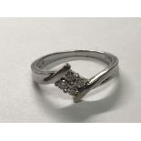 A ten carat white gold ring set with a pattern of four brilliant cut diamonds. ring size N