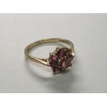 A 9carat gold ring set with a pattern of ruby coloured stones. Ring size L.