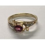 A 14carat gold ring set with a ruby coloured stone possible heat treated set with small diamonds.