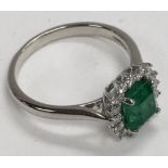 A platinum (950) cushion cut emerald and diamond set ring. (L.5).