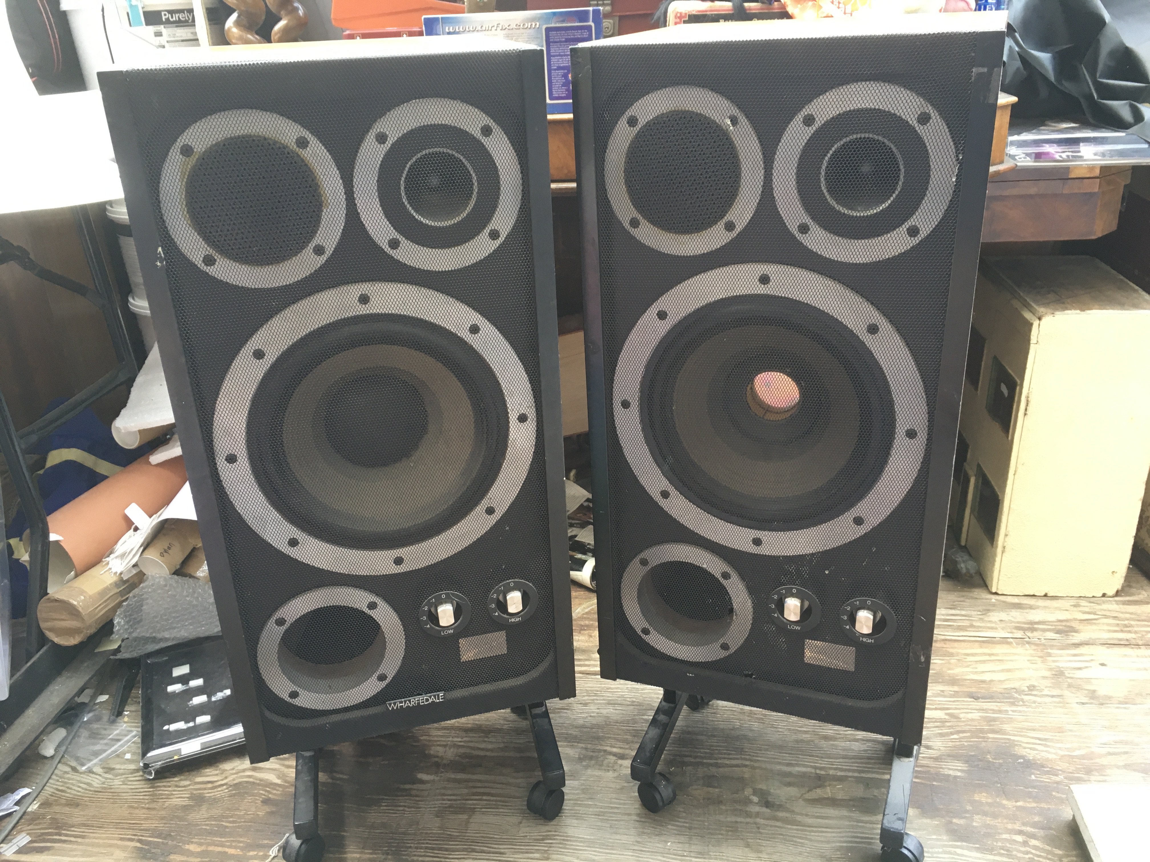 A pair of vintage Wharfedale E Fifty floor standing speakers, supplied with separate wheeled bases.