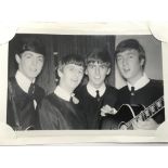 An original black and white photograph of The Beatles in 1963 posing backstage in their collarless