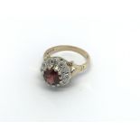 A 9carat gold ring set with a garnet flanked by di