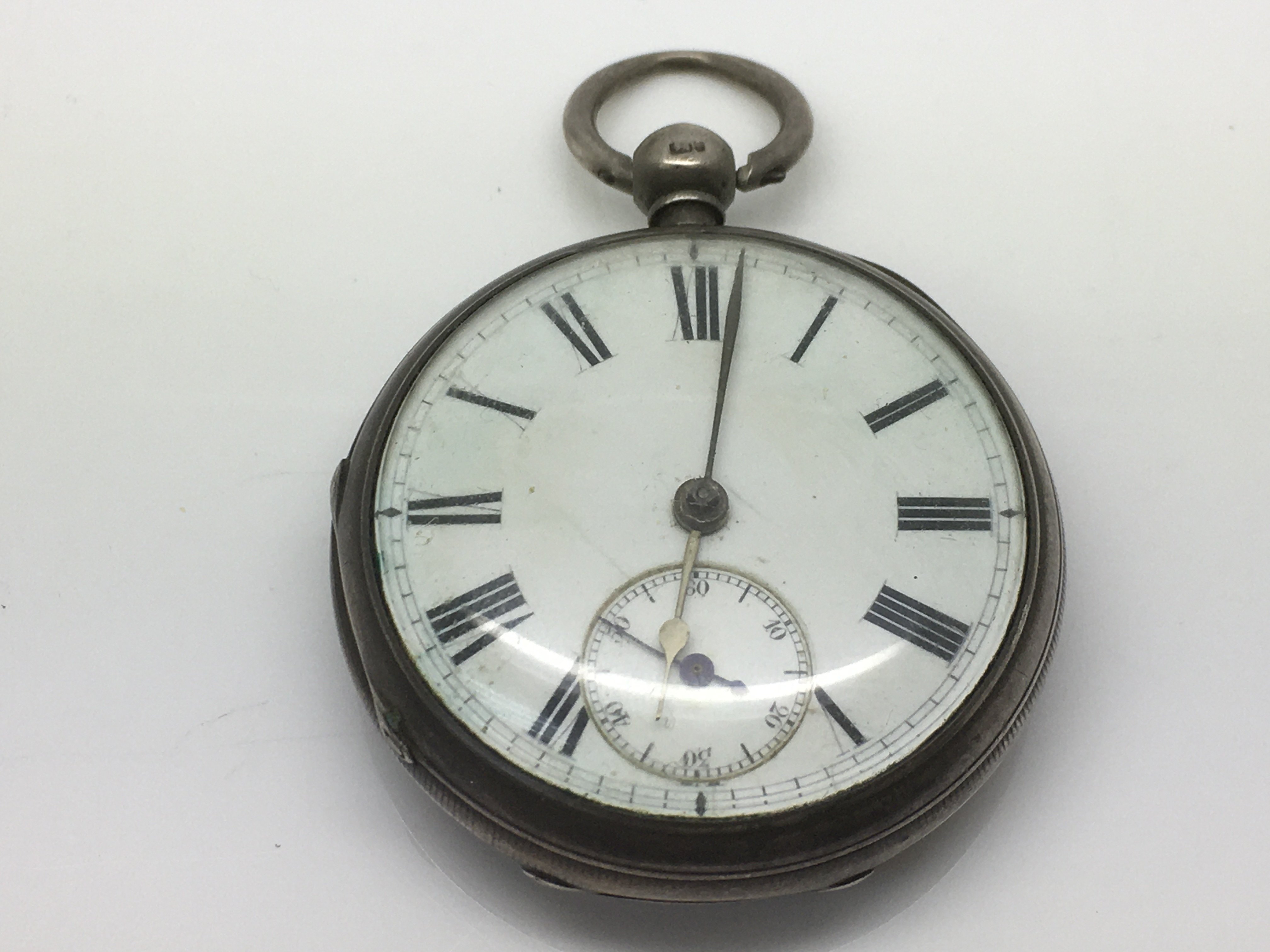 A silver pocket watch with Roman numerals and a su