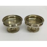 A pair of matching hallmarked silver pedestal tabl