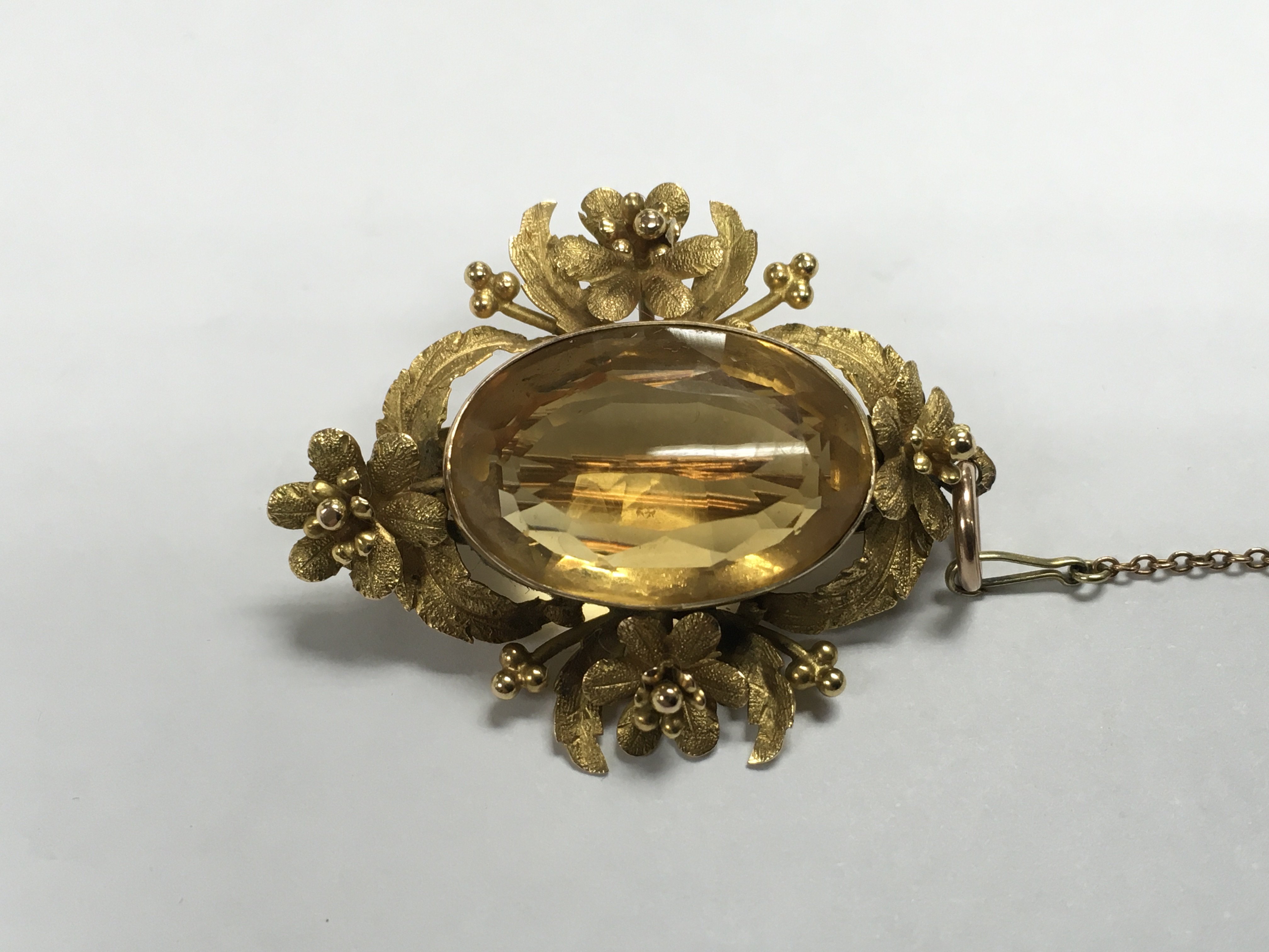 A unmarked Victorian brooch set with large cut citrine surrounded by a fancy foliate mount, 4 cm.