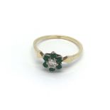 An 18ct gold diamond ring set with six emeralds in