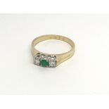 An 18carat gold ring set with an emerald flanked b