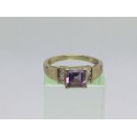 An 18ct gold ring set with a central amethyst, app