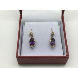 A pair of 9ct gold drop earrings set with amethyst