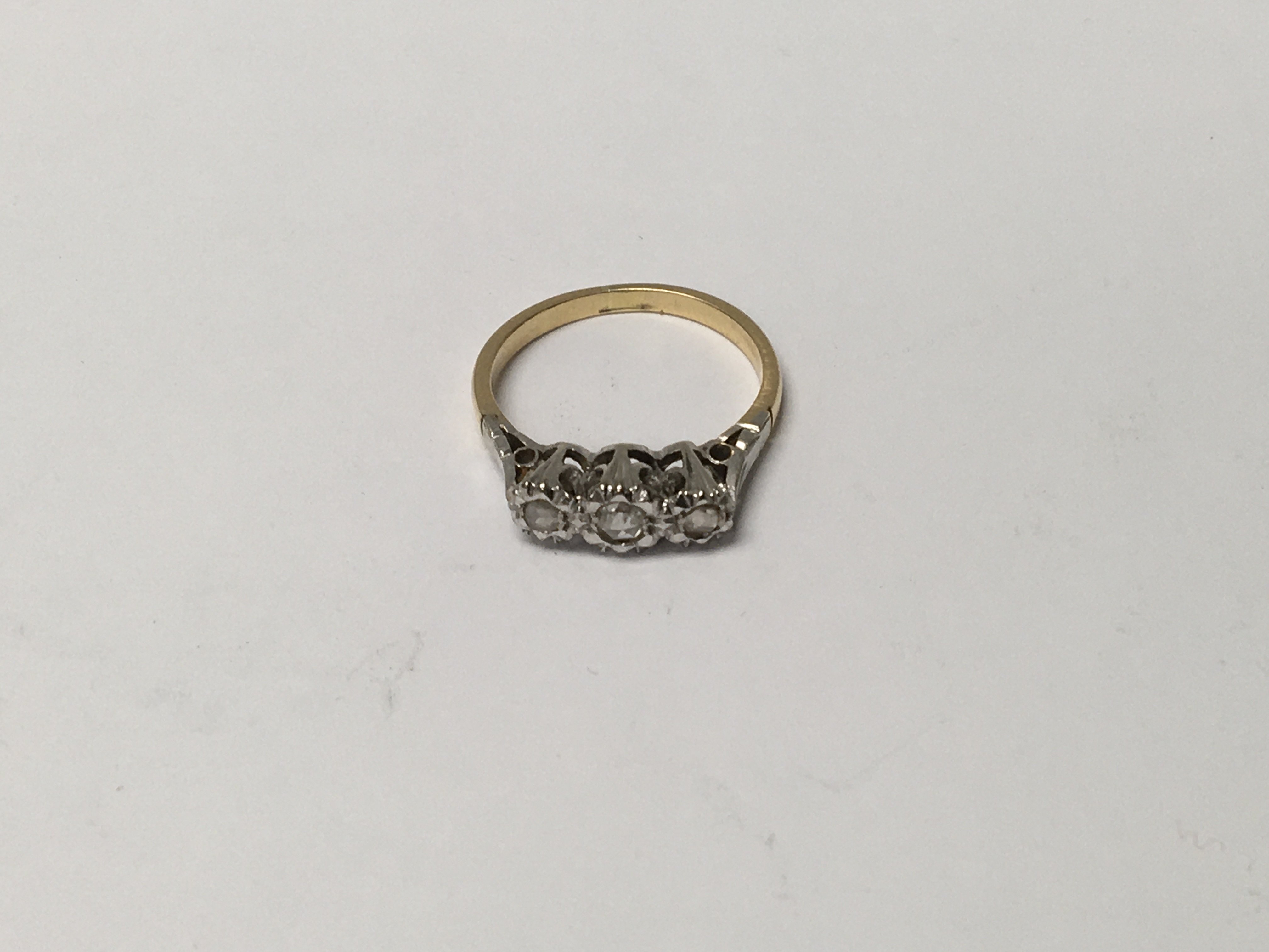 A unmarked gold ring inset with a row of three dia