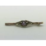 A 9ct gold brooch set with a central amethyst surr