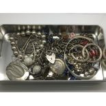 A tin of silver and white metal jewellery items.