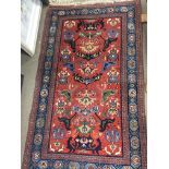 A hand knotted 20th Century Middle Eastern rug with a geometric pattern on a red ground with a light