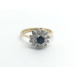 An 18carat gold ring set with a central sapphire and a cluster of diamonds ring size L-M