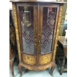 A marquetry two door display cabinet the glazed bow fronted door enclosing glass selfs on cabriole