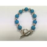 A silver and turquoise bracelet with a heart shape