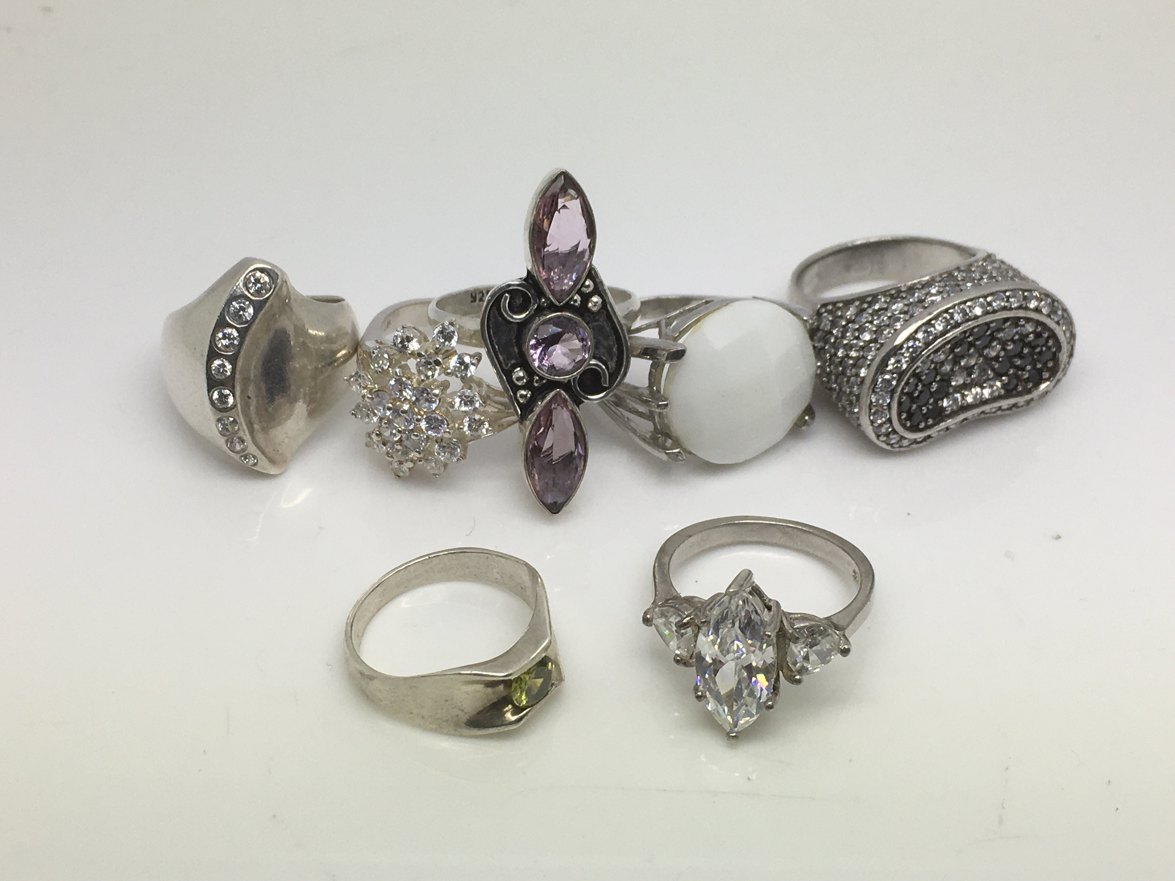 Seven silver rings set with various stones.