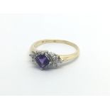 An 18carat gold ring set with amethyst flanked by a pattern of diamonds ring size Q.