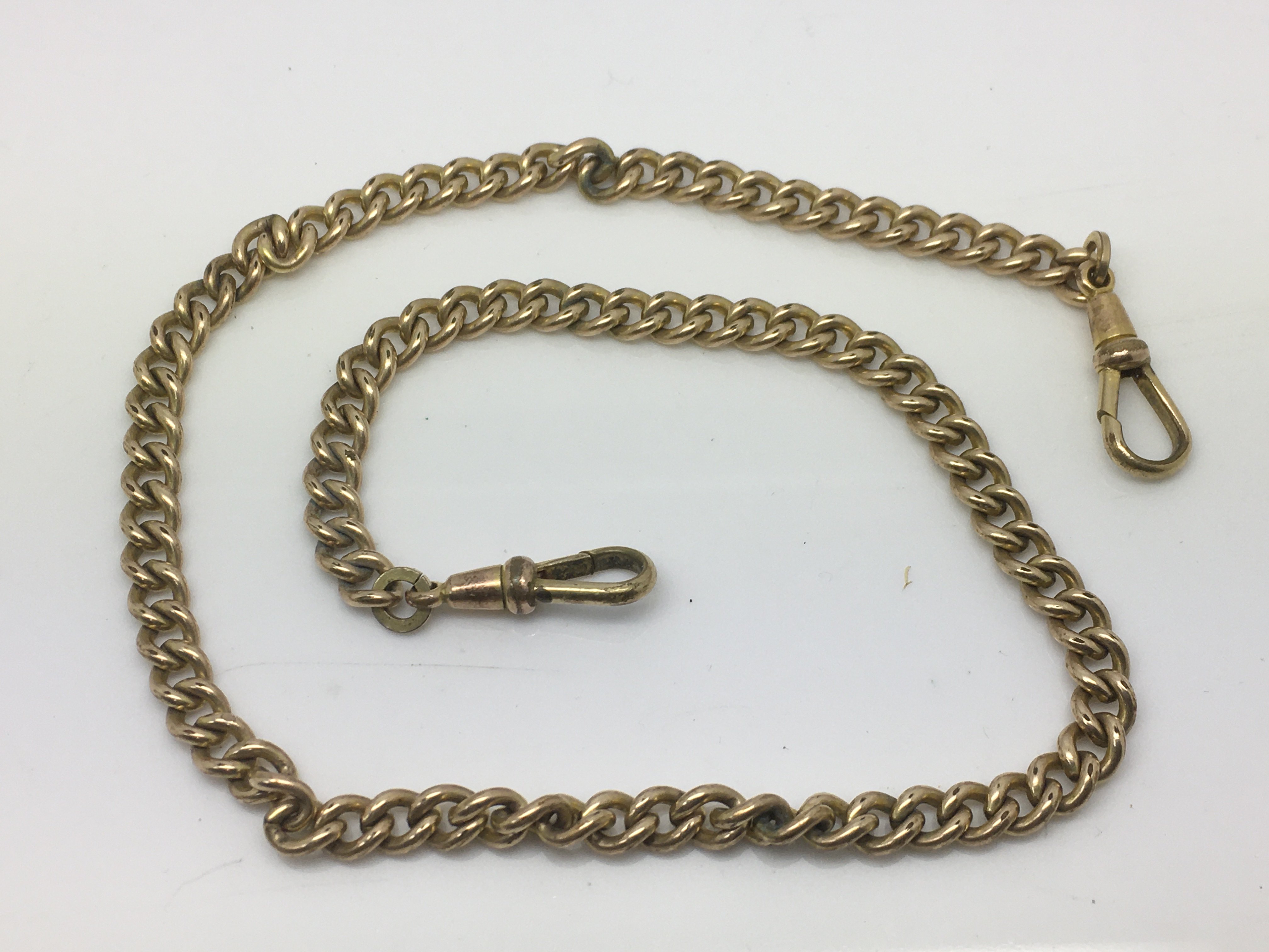 An antique gold plated watch chain and two fob cli