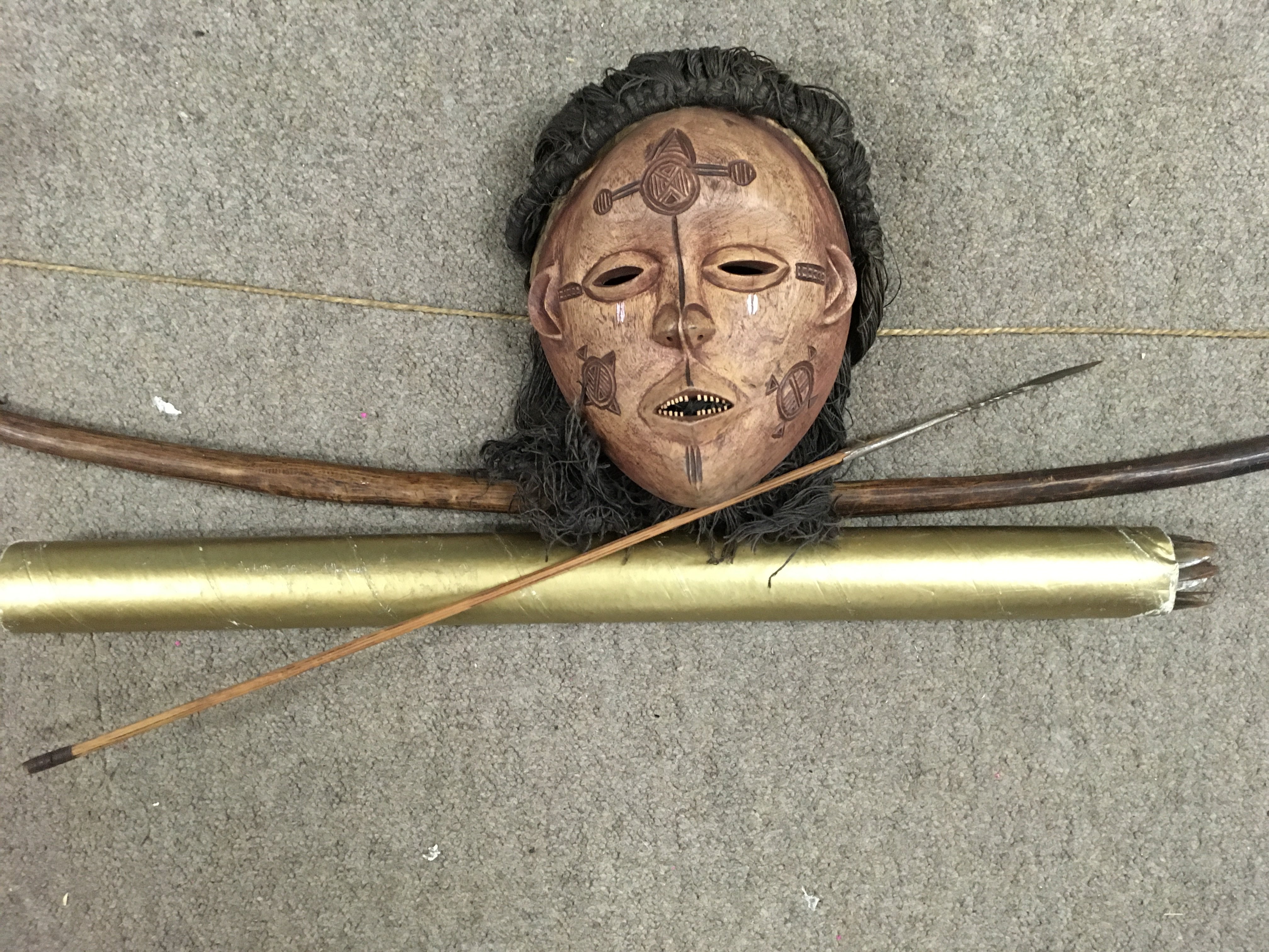 A tribal bow and arrow and a tribal face mask.