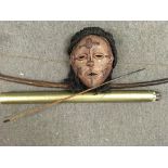 A tribal bow and arrow and a tribal face mask.