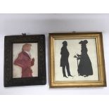 A gilt framed silhouette of a Victorian man and wo