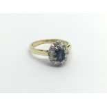 An 18carat gold ring set with a blue sapphire flanked by an oval of diamonds ring size K.