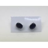 A pair of sapphire ear studs set in silver.