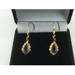 A pair of yellow metal earrings set with a sapphir