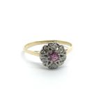 An unmarked gold ring set with a central ruby surrounded by diamonds in the form of a flowerhead,