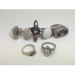 Seven silver rings set with various stones.