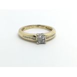 An 18ct gold diamond ring set with four diamonds and further small diamonds to the shoulders,