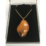 An amber pendant on a silver gilt chain.