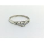 An unmarked white gold solitaire diamond ring set with a princess cut diamond and with further small