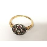 An Antique 18carat gold ring with an open scroll circular set with a pattern of ruby and old cut