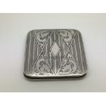A silver compact with engraved design.