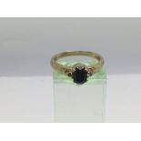 A 9ct gold ring set with a central sapphire, appro