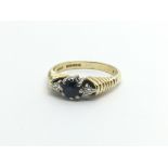 An 18carat gold ring set with a blue sapphire flanked by two diamonds ring size J.