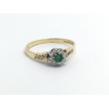 An 18ct gold eing set with a central emerald surrounded by small diamonds in the form of a